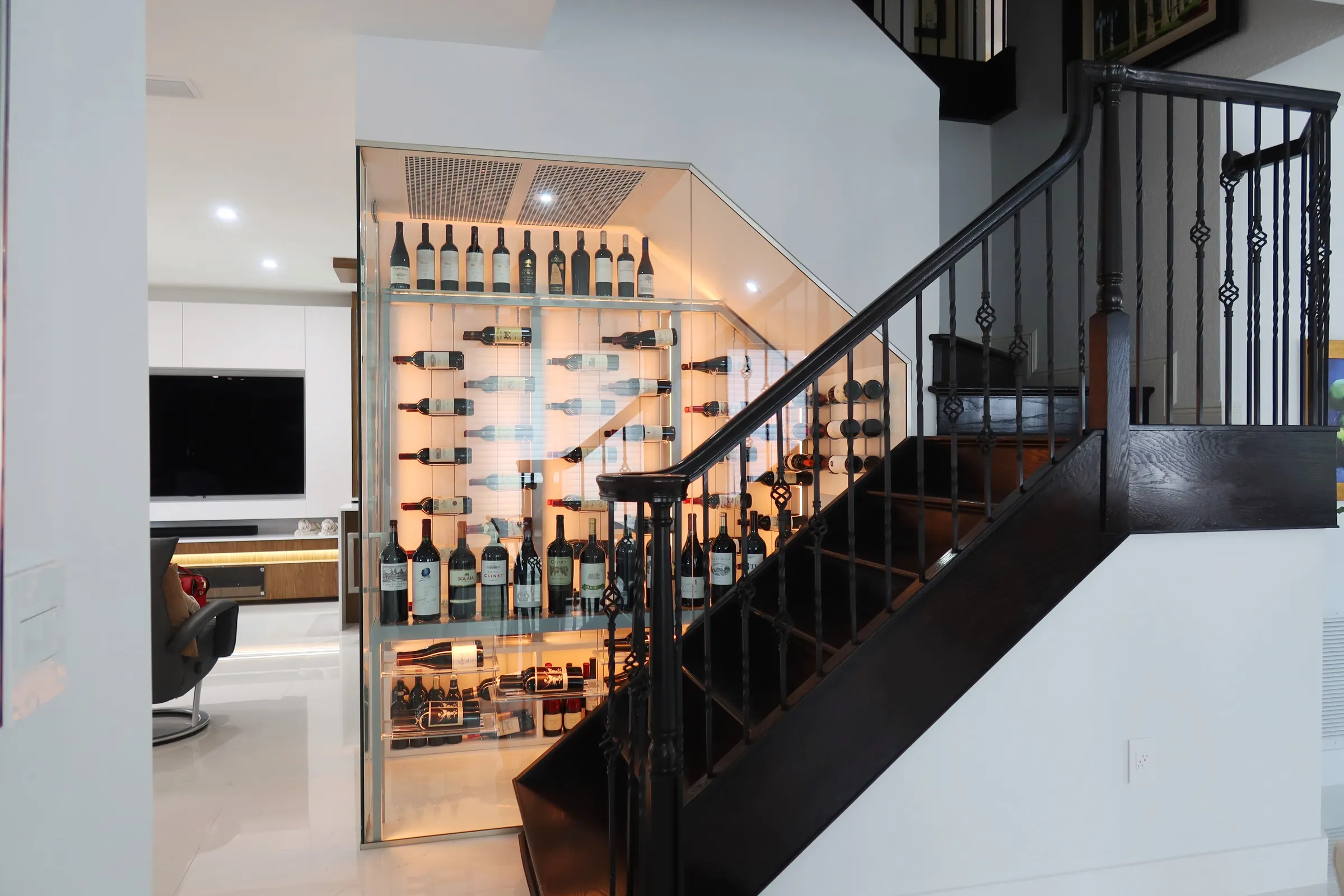 Custom understairs wine cellar Miami featuring glass enclosure, illuminated wine racks, and luxury wine storage design — photograph 2 of 3