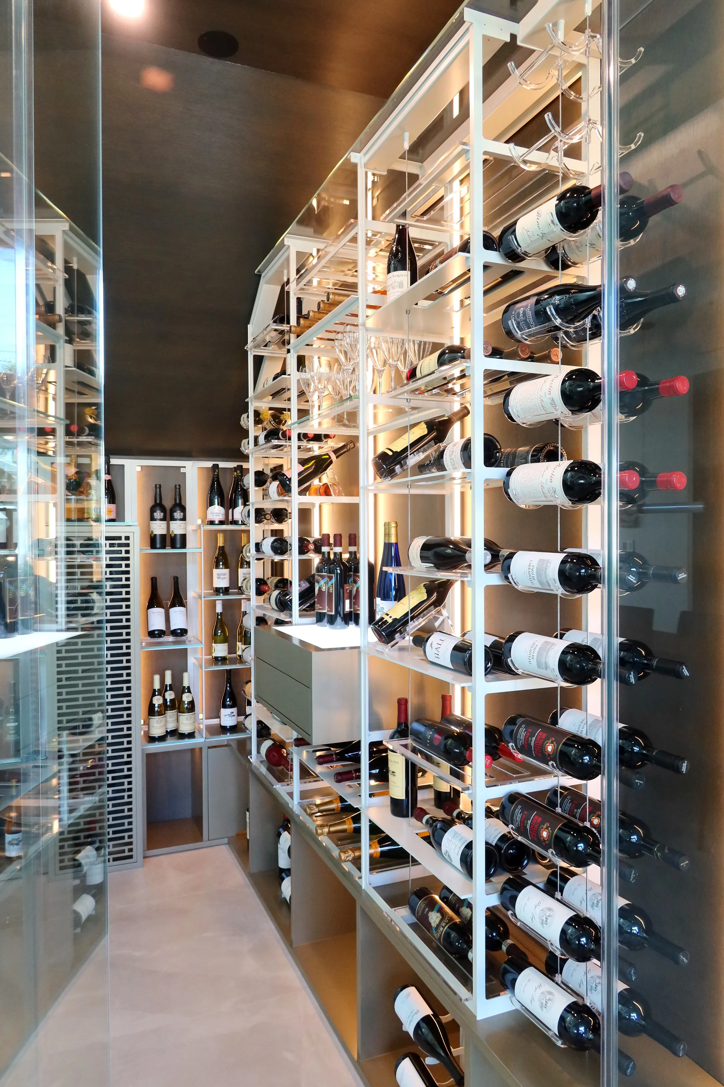 understairs wine room in south Florida, glass enclosures, wall-mounted metal wine racks, contemporary wine cellar design, luxury wine storage — photograph 1 of 4